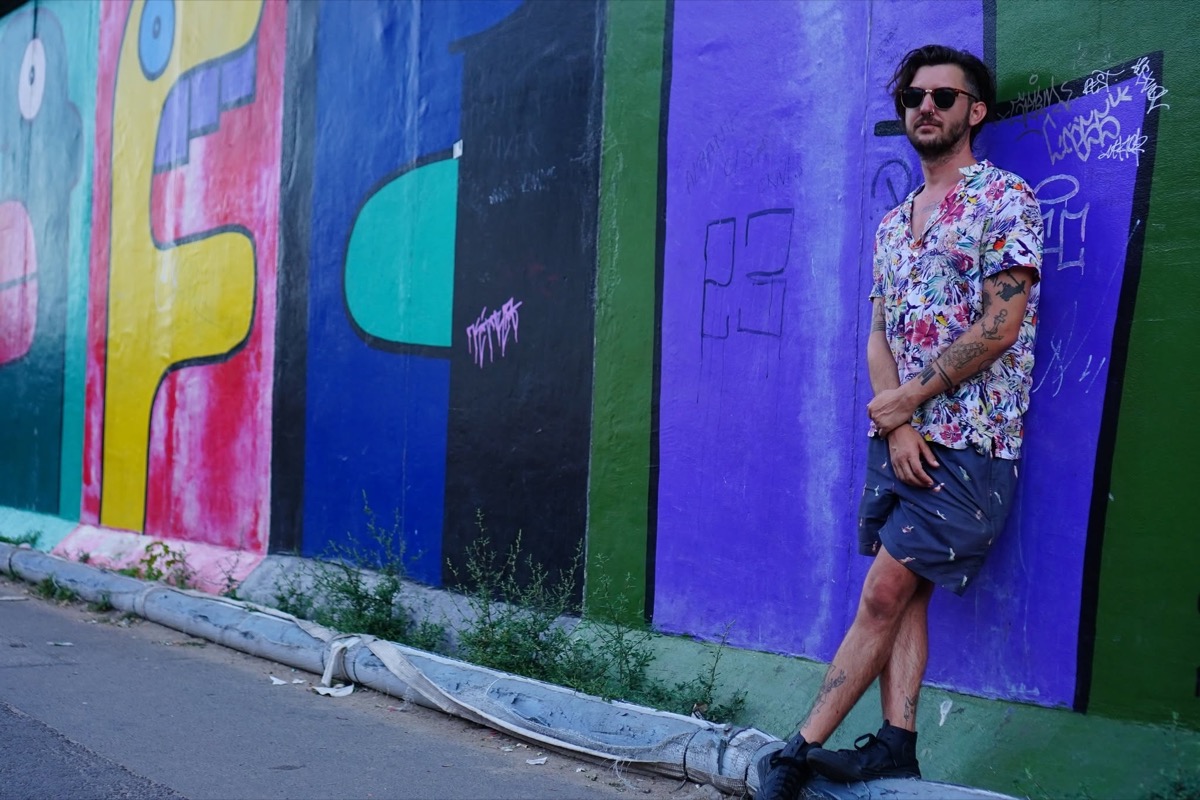 Carl Tomich standing beside a colourful mural